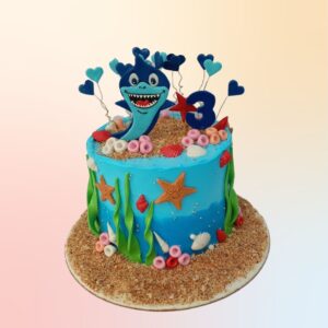 Baby Shark Customised Birthday Cake 1 Kg,Customized Baby Shark cake featuring colorful underwater scenes with friendly shark family, seaweed, and bubbles on a round 1kg base.