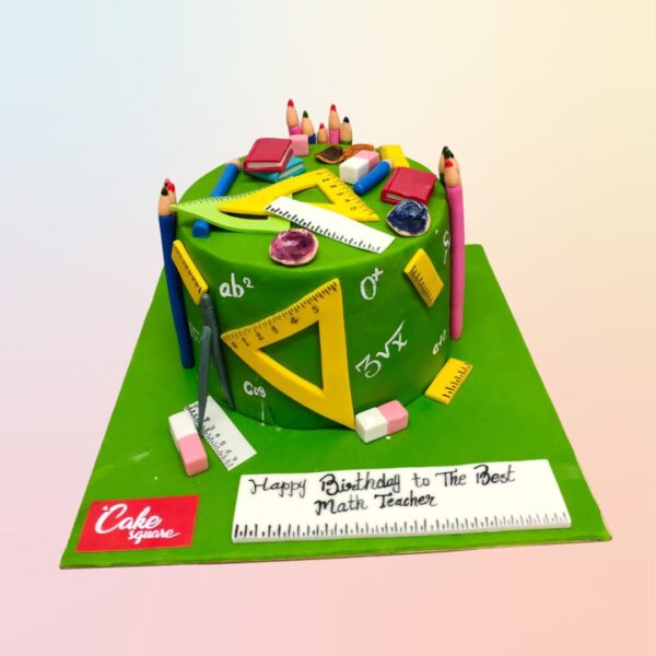 Best Math teacher Fancy Birthday Cake 1 Kg. Book-shaped birthday cake decorated to resemble a math textbook, with fondant numbers, equations, and geometric shapes. Includes a miniature chalkboard with "Happy Birthday" written in chalk.