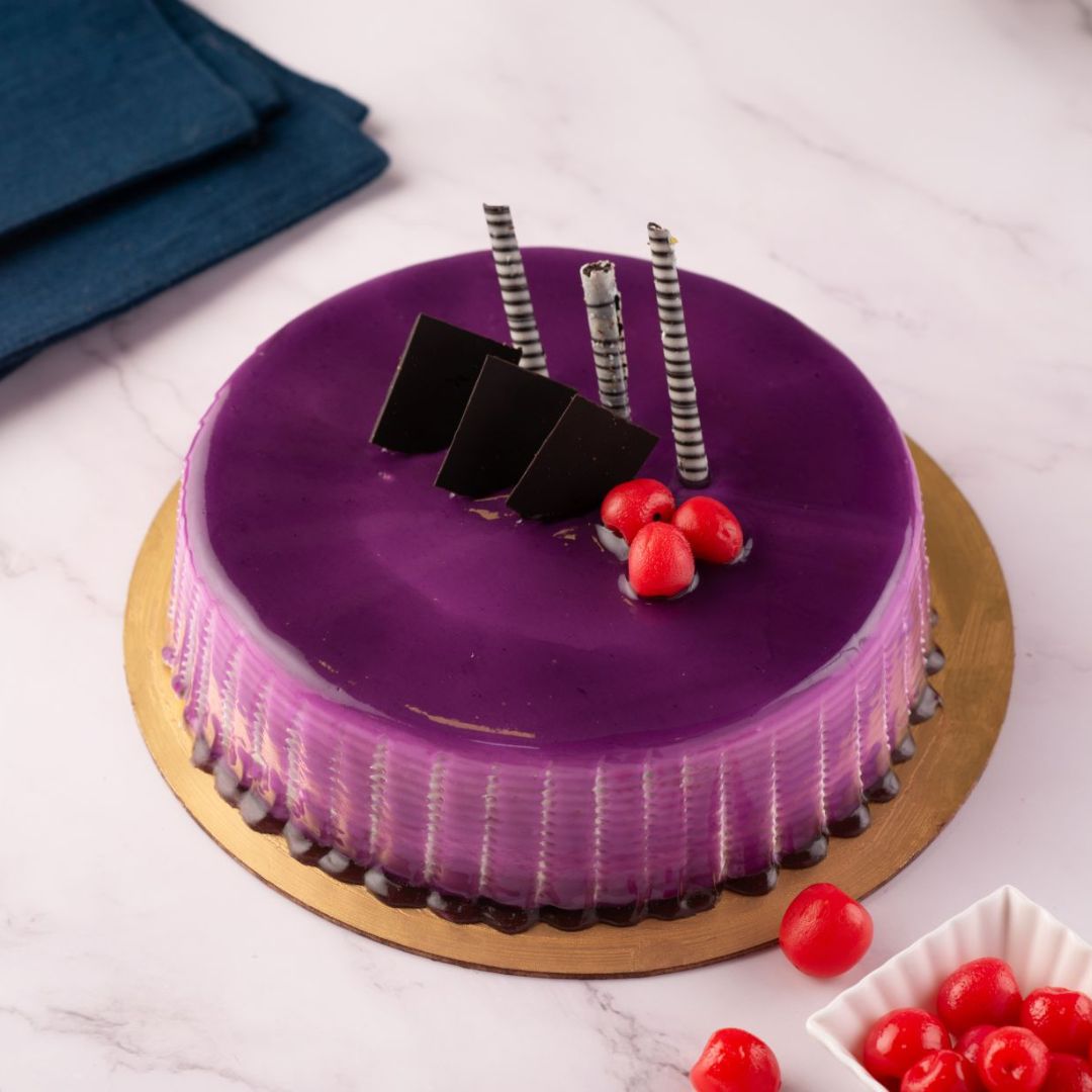 A purple round shaped cake that has edges on the sides to show off the cheese and decorated with couple of cherries and chocolate pipings is our Blackcurrant Cheese Birthday Cakes 500 gms. Order Now.