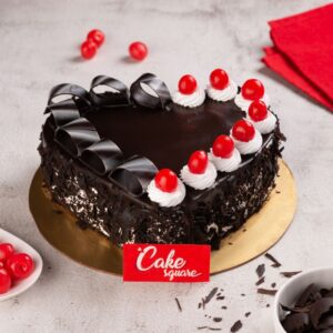 Enjoy our Chocolate Heart Black Forest Anniversary Cake 1 kg decorated with white cream and strawberry swirls on one side and chocolate toppings on the other side. Order now from Cake Square Chennai.
