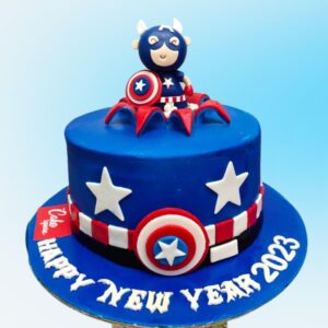 Cool Captain America Cake 1 Kg featuring the hero's iconic shield design, red, white, and blue fondant layers, and "Happy Birthday" written in comic-style font. Topped with a miniature fondant Captain America figure.