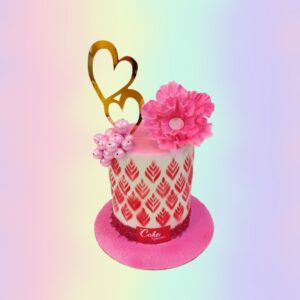 A white cake self designed with pink flower and a double heart topper is Flower Anniversary Cake 1 Kg made by Cake Square team.