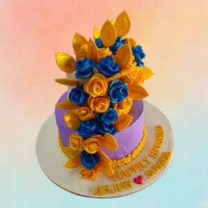 A mini 3 Kg wedding cake with a combination of purple and gold trailed from top to bottom with colourful purple and gold roses. Flower bride to be 3 Kg engagement cake is made by Cake Square Team.
