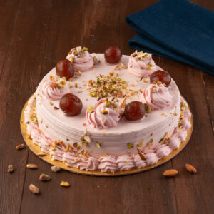 A round 1 Kg cake with light pink frosting, decorated with a cascade of mini gulab jamuns and pistachio.