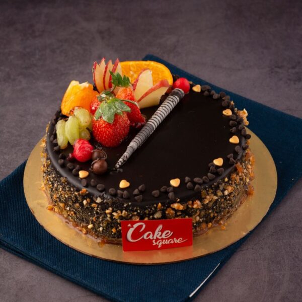 A round 1 kg Fruitful Fantasy Chocolate Birthday Cake with ganache coating, adorned with chocolate and glazed fresh fruits.