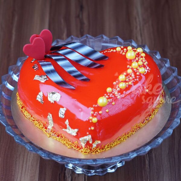 One kg heart-shaped anniversary cake in red, decorated with romantic kiss-themed designs.Made by Cake Square team.