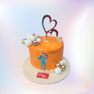 A yellow beautiful cake, a man carrying a woman and a double heart shape cake topper with some chocolate balls to make it beautiful is Anniversary theme 1 Kg Cake made by Cake Square.