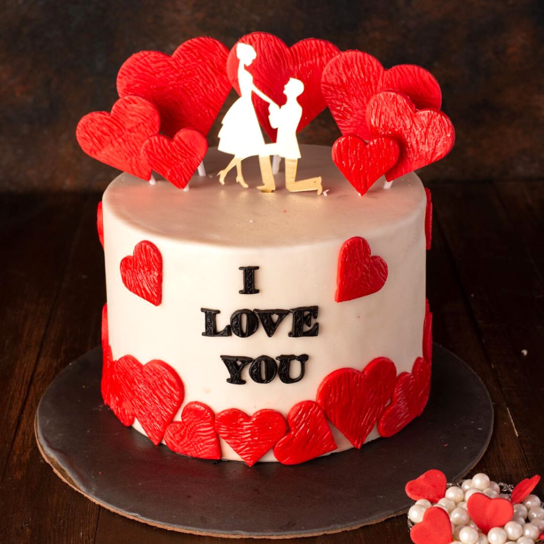 A proper proposal cake filled with textured hearts around in our Promised Love 1 Kg Anniversary Cake with a beautiful cake topper by Cake Square Chennai.