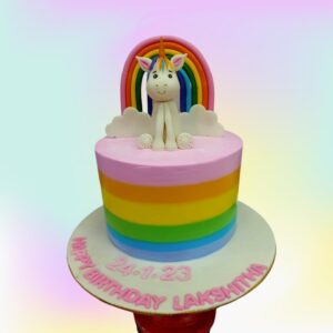 Rainbow Unicorn Girls Birthday Cake 2 Kg Two-tier rainbow-colored cake with unicorn topper, cloud decorations, and gold accents