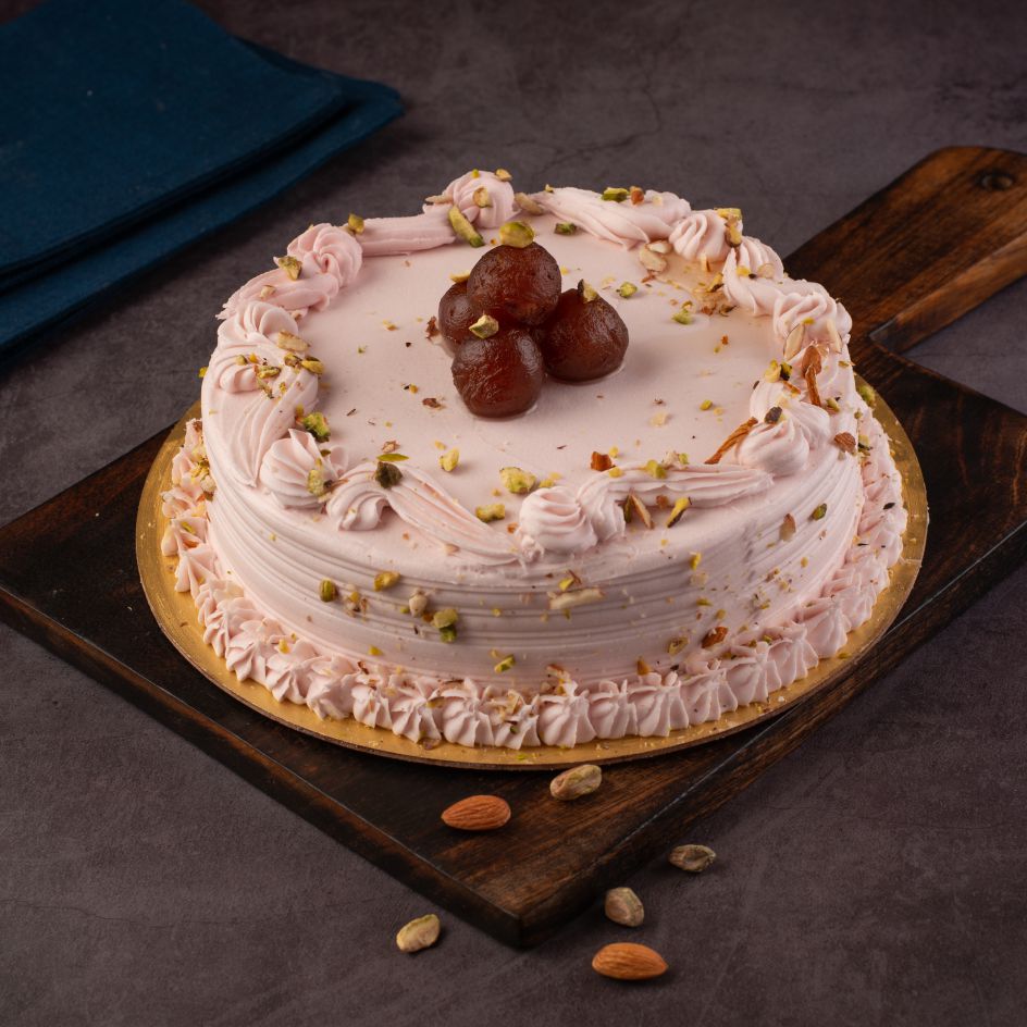 A round 1/2 Kg cake with rose-tinted frosting, topped with whole gulab jamuns and pistachios.