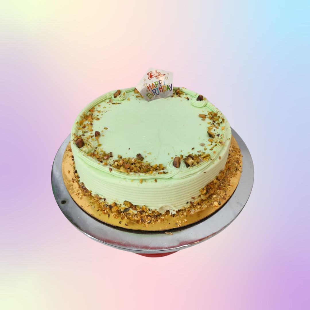 A round 1 kg cake with light green frosting and topped with pistachios.