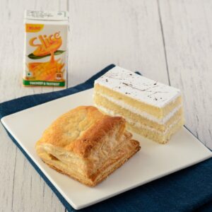 Buy Vanilla pastry and Veg puff Combo. Elegant plate featuring a creamy vanilla pastry alongside a golden, flaky vegetable puff.