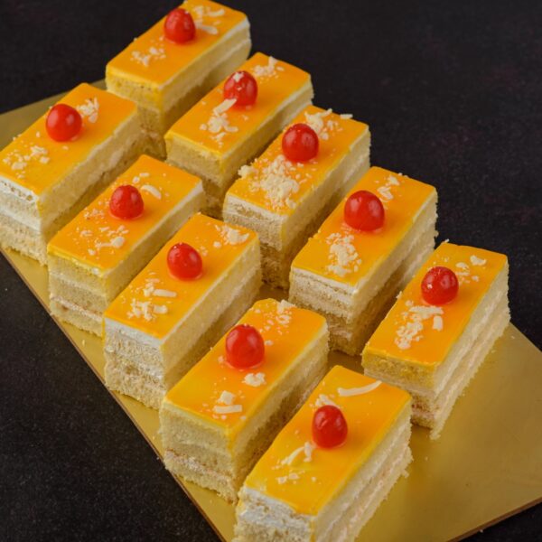 Mango cake piece 80 gms. Vibrant yellow mango cake slice with mango chunks, 80 grams.