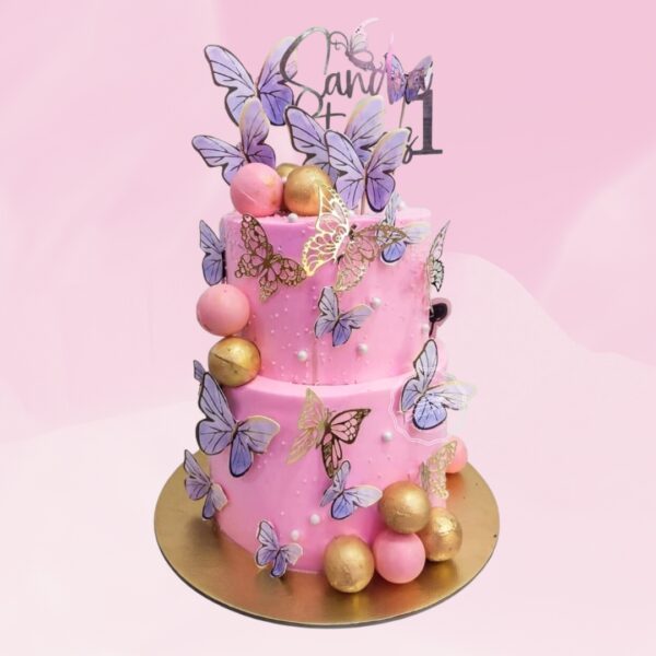 A pink two tier cake decorated with 3 d butterflies and a golden faux balls and edible golden sheet as Beautiful Butterfly First Birthday Cake 5 Kg