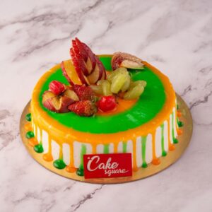 "Fresh Apple Mango 1 Kg Birthday Cake: Round cake with cream-colored frosting, topped with a pattern of fresh red apple and yellow mango slices, and a 'Happy Birthday' sign."