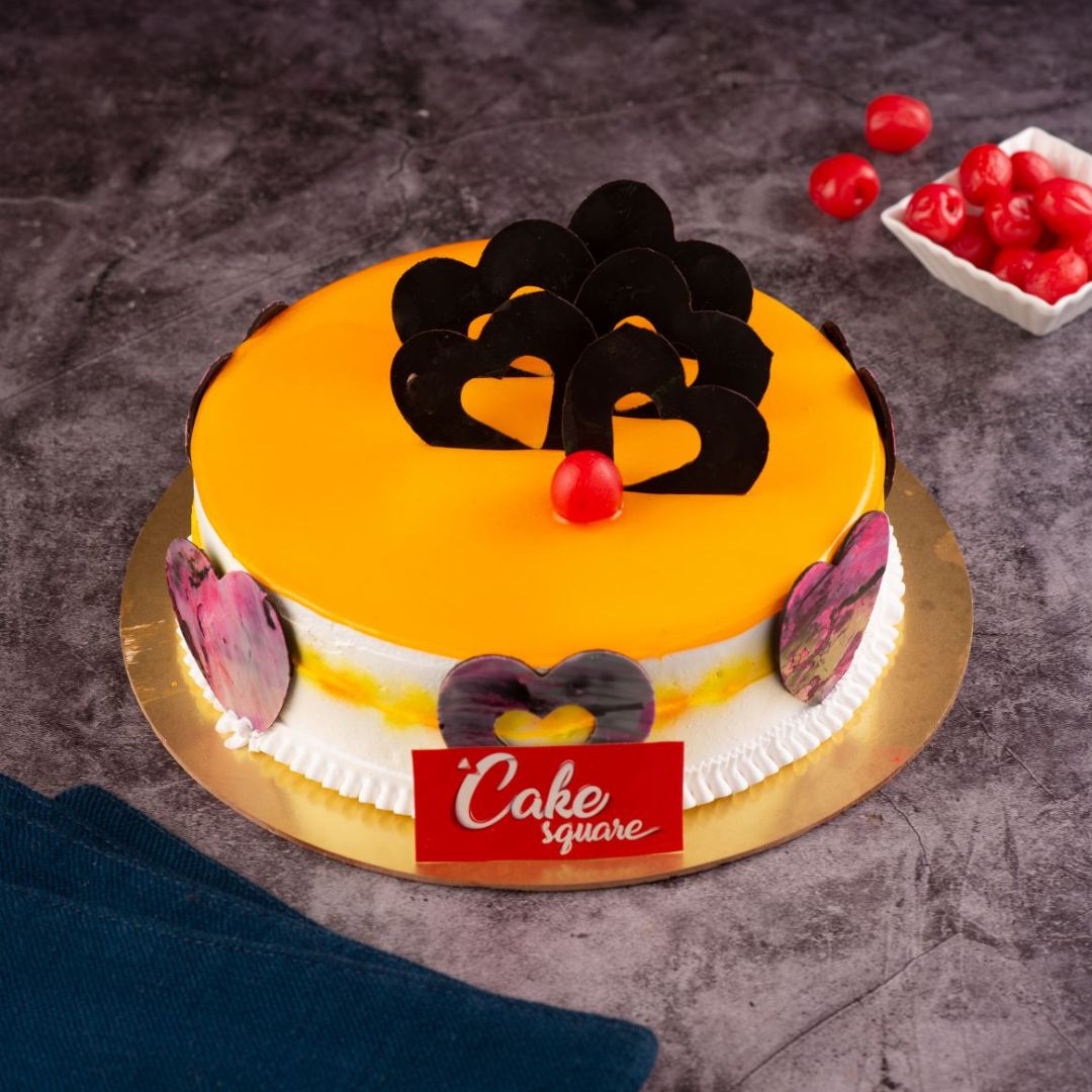 A round half kg yellow colour cake with best chocolate ganche designs in herat shape in ourLuscious Mango 500 gms Birthday Cake. Made by Cake Square Team