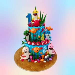 "Baby Shark Theme First Birthday Cake 4 Kg featuring vibrant Baby Shark characters, perfect for a fun and playful first birthday celebration."