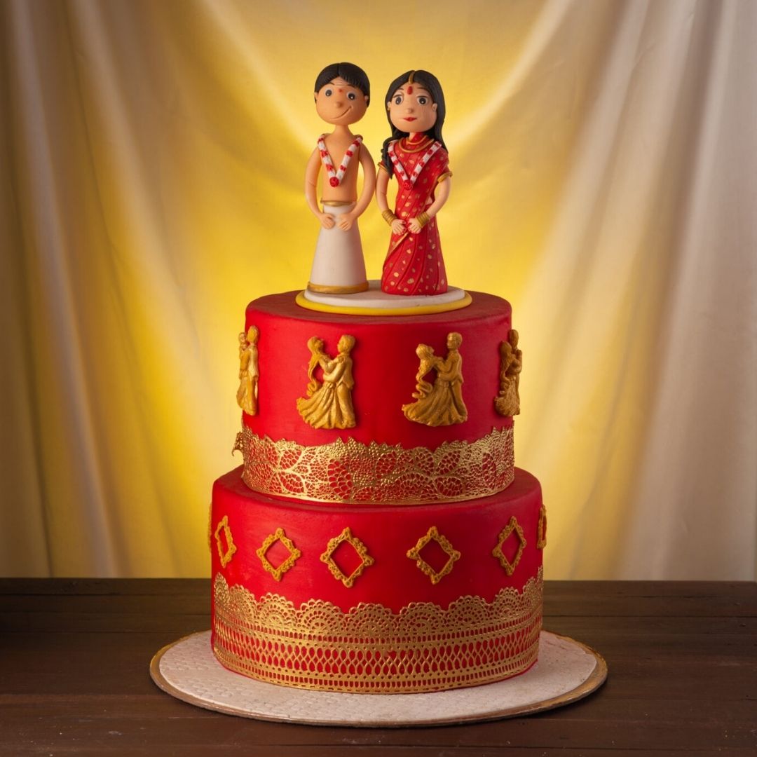 Charming Cute Traditional Couple Wedding Cake 4 Kg featuring multiple tiers adorned with cultural patterns and topped with adorable figurines of a couple in traditional attire, created by Cake Square Chennai.