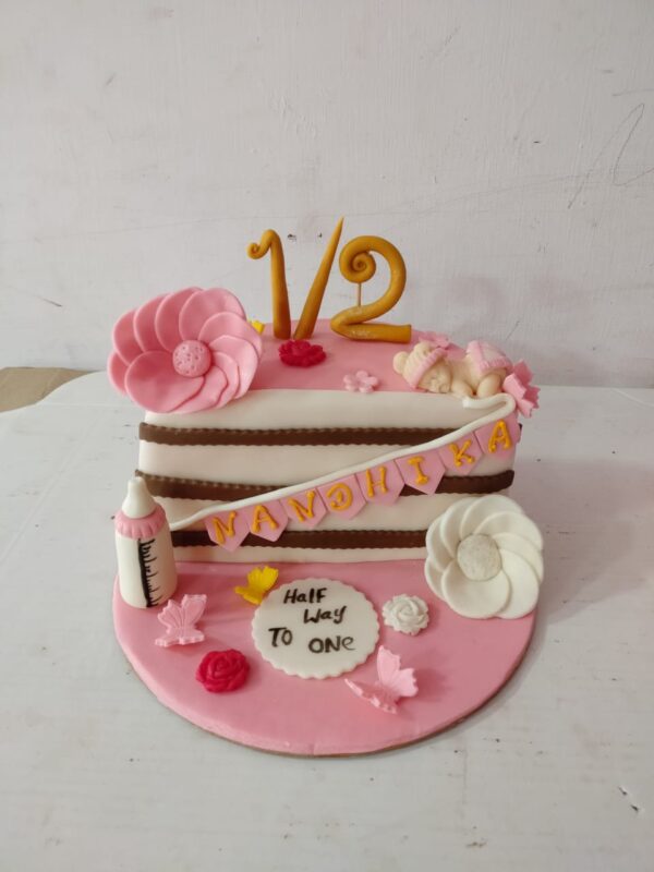 "Girls Pink Theme Half Birthday Cake 1 Kg featuring vibrant pink decorations, perfect for a charming half-birthday celebration."