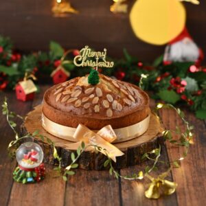 A large Authentic Almond cake 1kg on a cake stand, showing its golden-brown crust and almond-studded top.