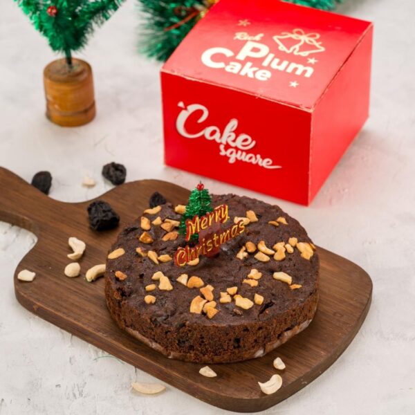 A festive Christmas Rum Infused Nuts Plum Cake 200 gms displayed on a holiday-themed table, showcasing its rich colour and nutty toppings.